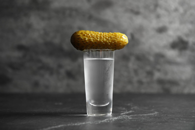 Photo of Cold Russian vodka with pickle on black table