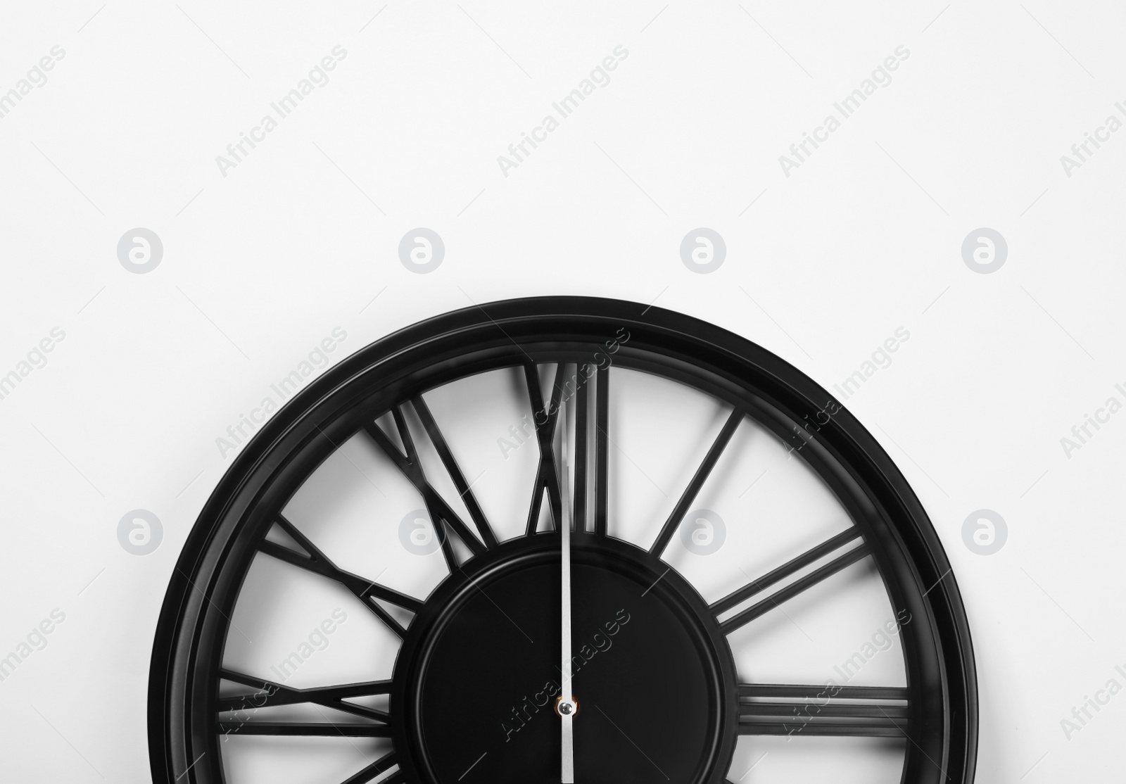 Photo of Stylish analog clock hanging on white wall, space for text