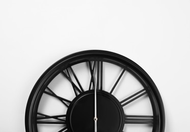 Stylish analog clock hanging on white wall, space for text