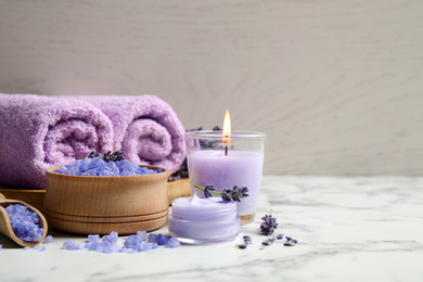 Photo of Cosmetic products and lavender flowers on white marble table. Space for text