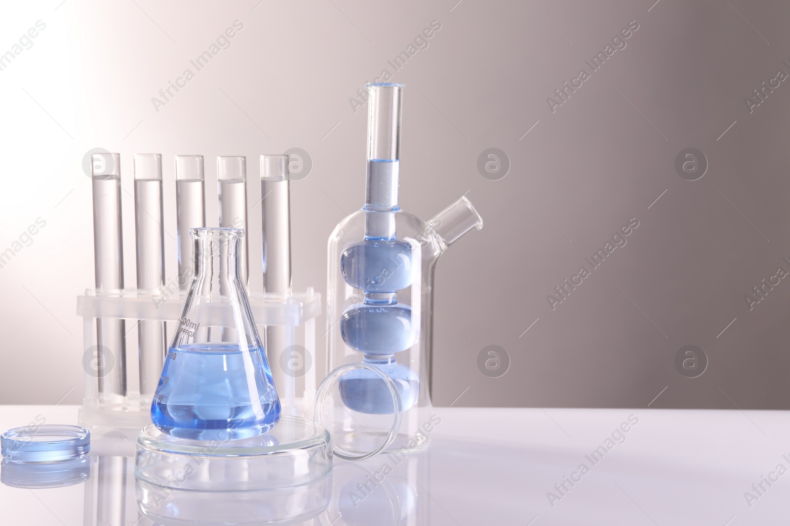 Photo of Laboratory analysis. Different glassware on table against light background, space for text