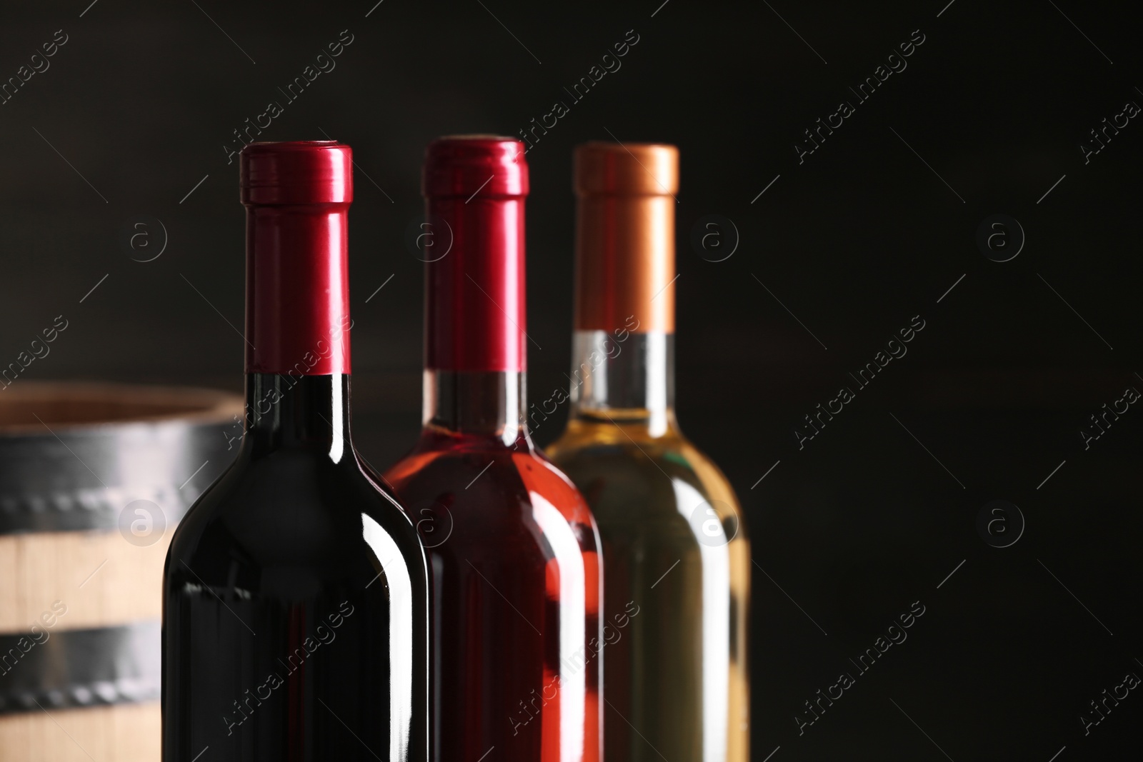 Photo of Bottles of different wine on dark background, closeup. Space for text