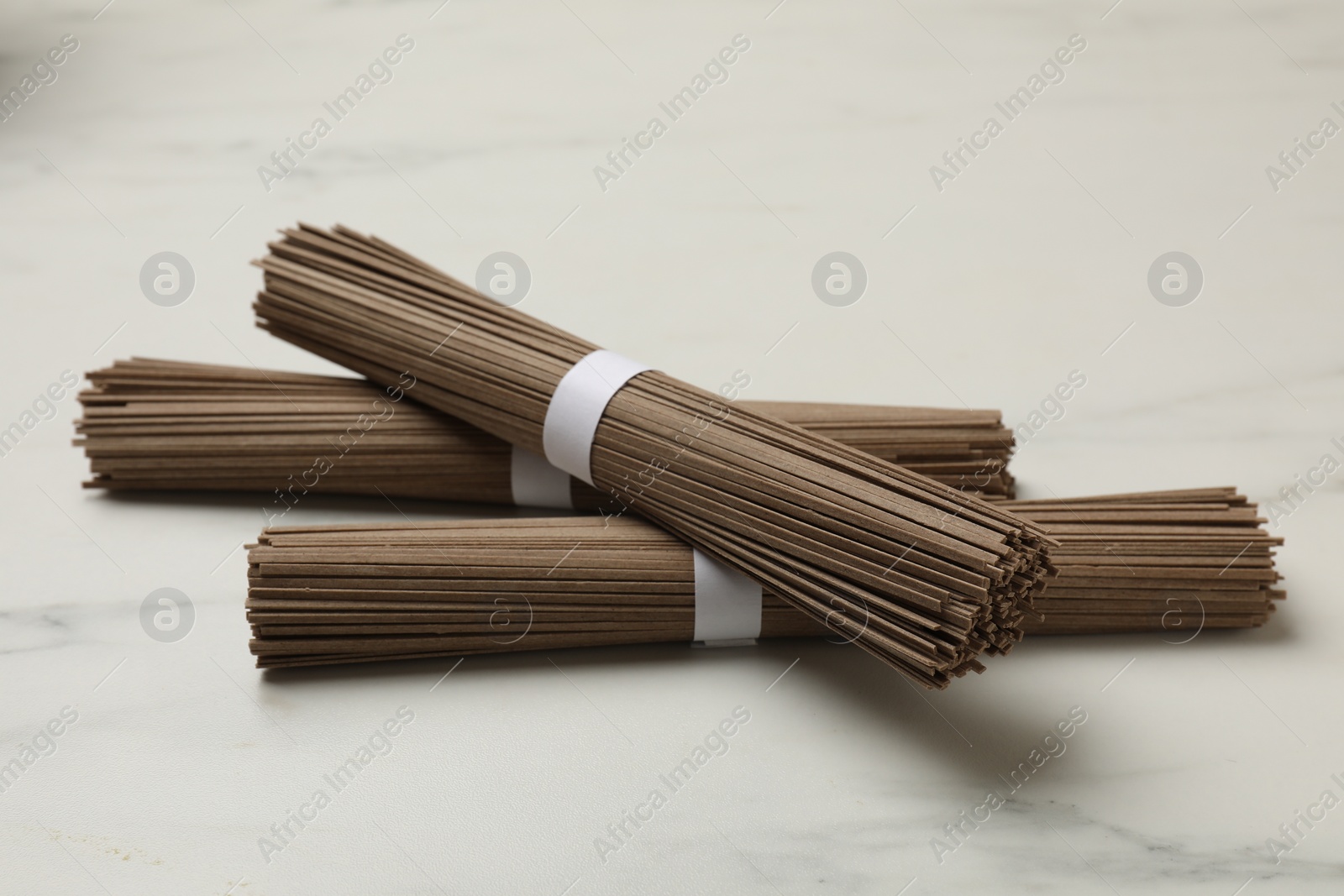 Photo of Uncooked buckwheat noodles (soba) on white marble table