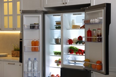 Open refrigerator full of different products in kitchen