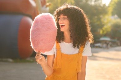 Portrait of happy woman with cotton candy outdoors on sunny day