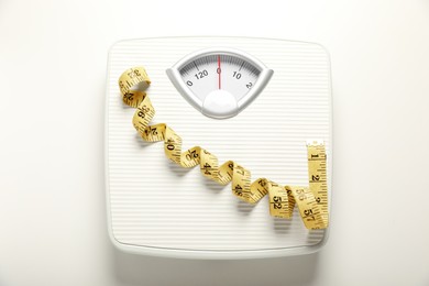 Photo of Scales and measuring tape on white background, top view