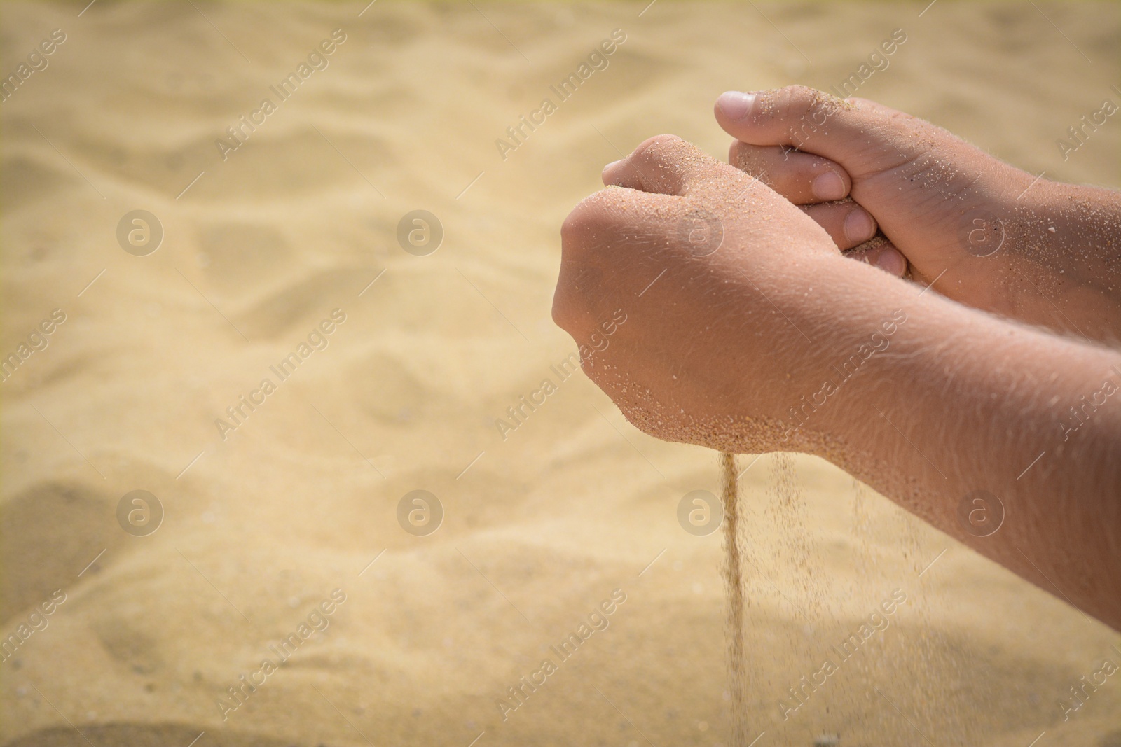 Photo of Child pouring sand from hands on beach, closeup with space for text. Fleeting time concept