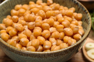Photo of Bowl with delicious chickpeas on table, closeup. Hummus ingredient