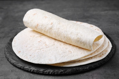 Photo of Slate plate with corn tortillas on grey background. Unleavened bread
