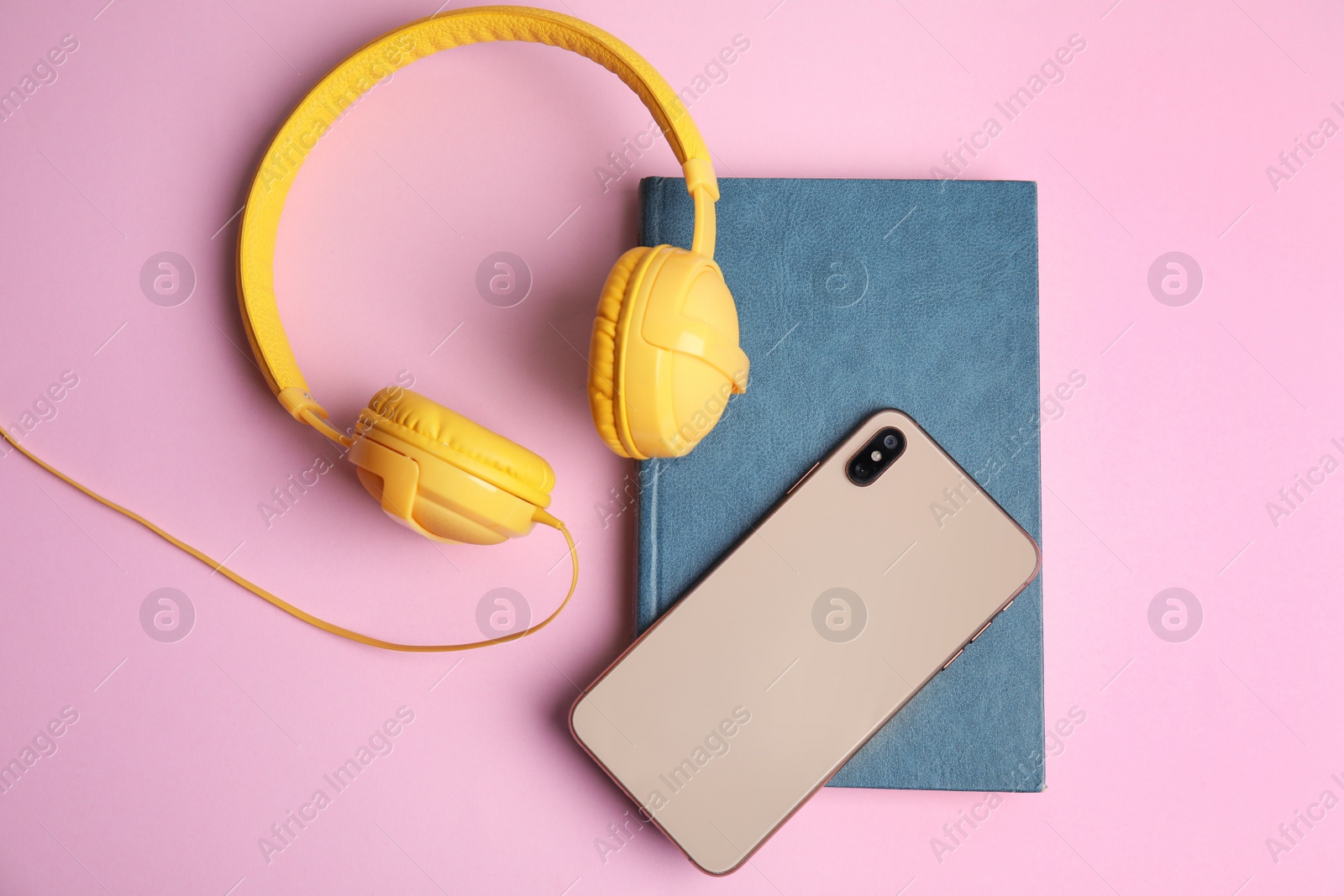 Photo of Book, modern headphones and smartphone on pink background, flat lay