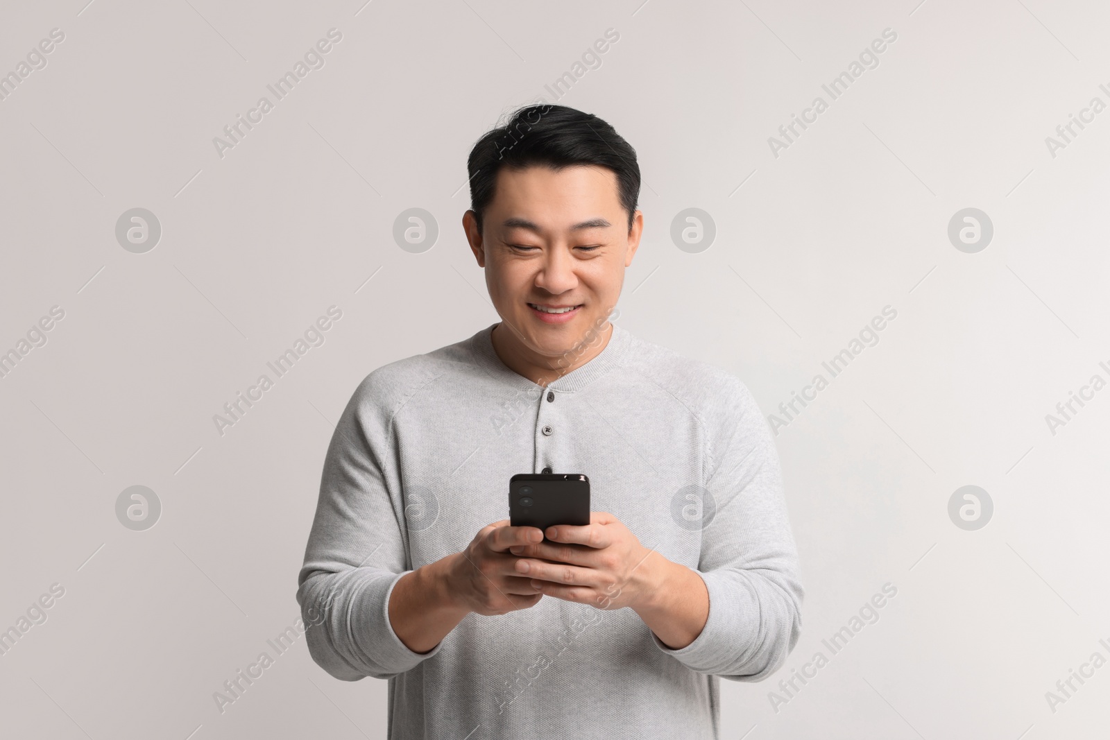 Photo of Portrait of happy man with smartphone on light background