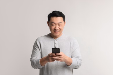 Portrait of happy man with smartphone on light background