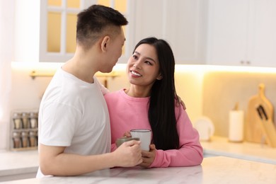 Photo of Lovely couple with cups of drink enjoying time together in kitchen, space for text