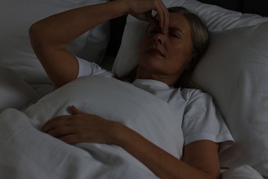 Woman suffering from headache in bed at night