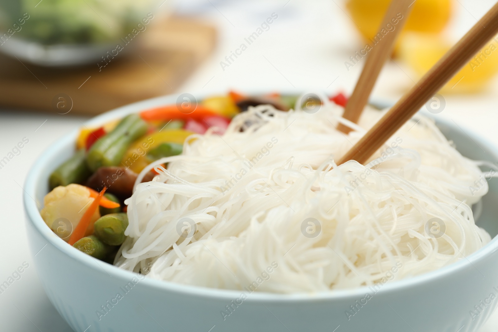 Photo of Tasty cooked rice noodles with vegetables in bowl, closeup