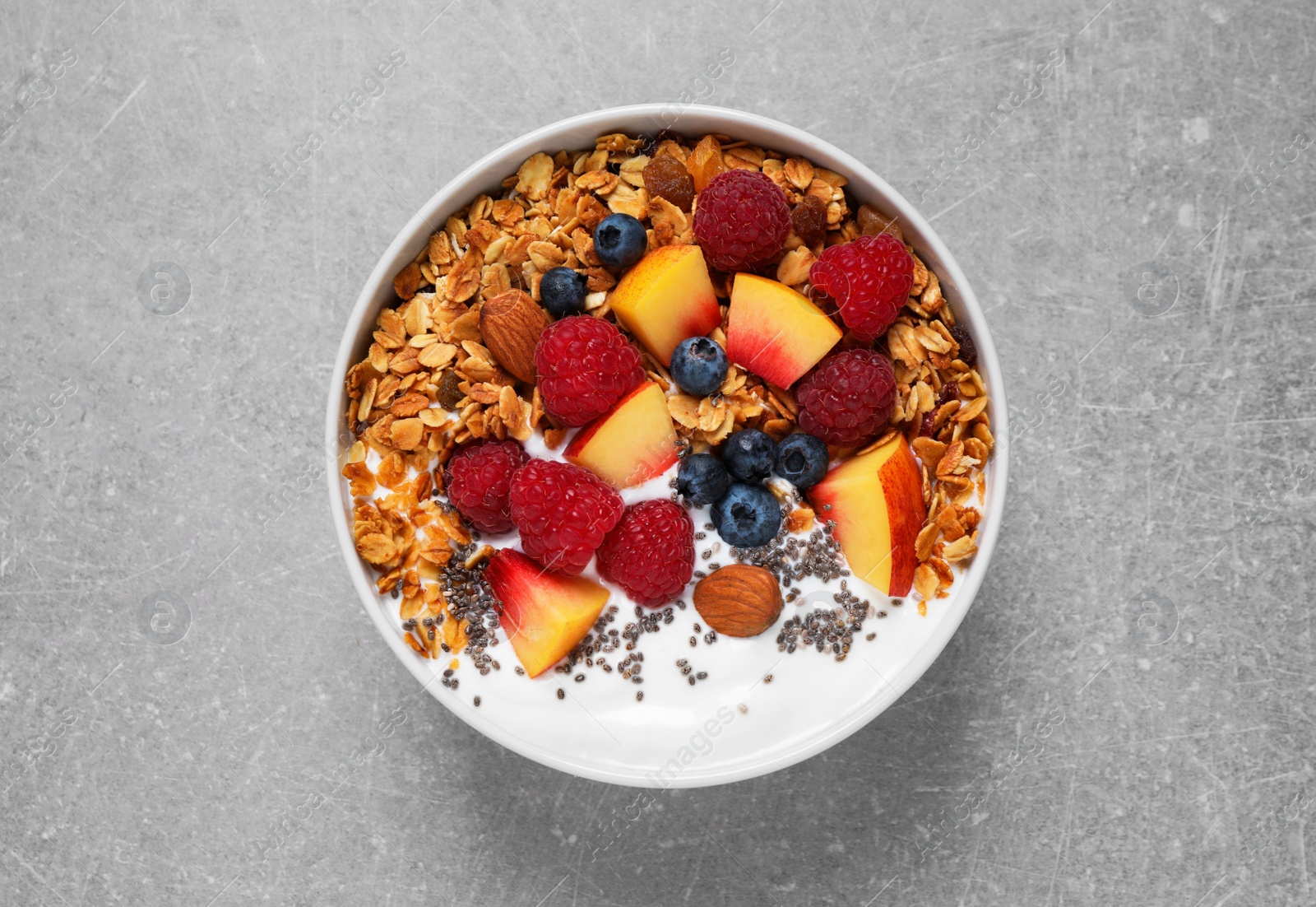 Photo of Tasty homemade granola with yogurt on grey table, top view. Healthy breakfast