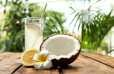 Photo of Composition with glass of coconut water and lemon on wooden table