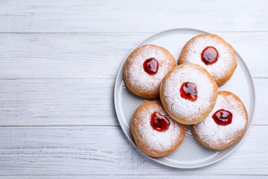 Photo of Hanukkah doughnuts with jelly and sugar powder on white wooden table, top view, Space for text
