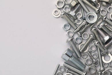 Photo of Different metal bolts and nuts on white background, flat lay. Space for text