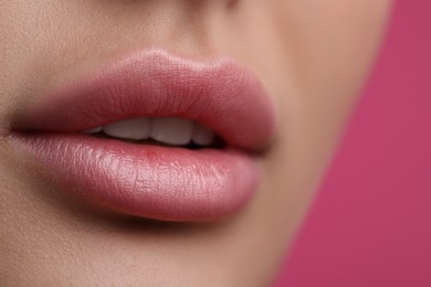 Photo of Young woman with beautiful lips on pink background, closeup view