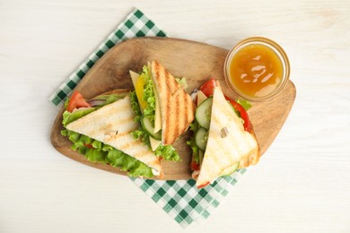 Delicious sandwiches with vegetables and cheese on white table, top view