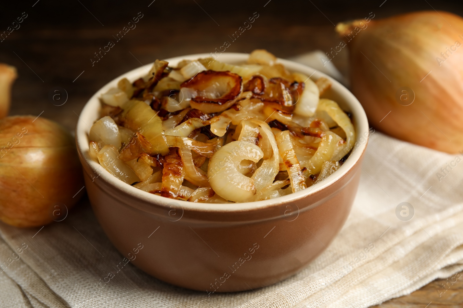 Photo of Tasty fried onion in bowl on napkin, closeup