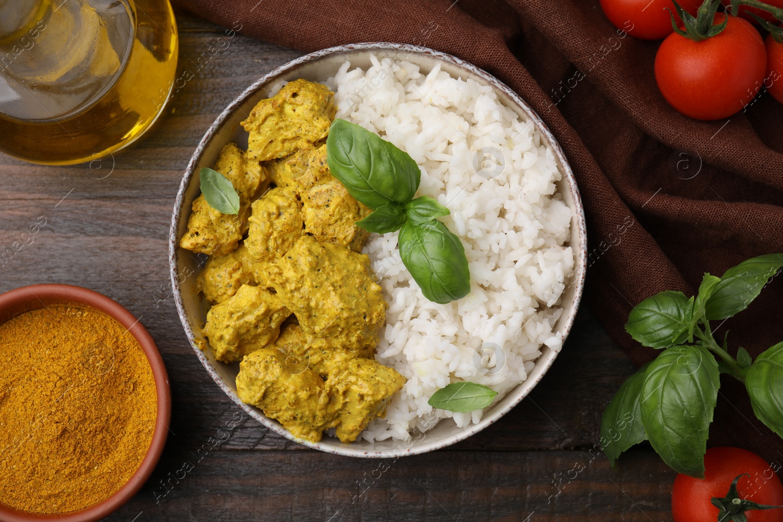 Photo of Delicious rice, chicken with curry sauce and products on wooden table, flat lay