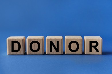 Wooden cubes with word Donor on blue background