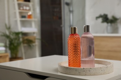 Bottles of shower gels on white table in bathroom, space for text