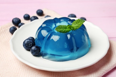 Plate of delicious blue jelly with berries on pink wooden background