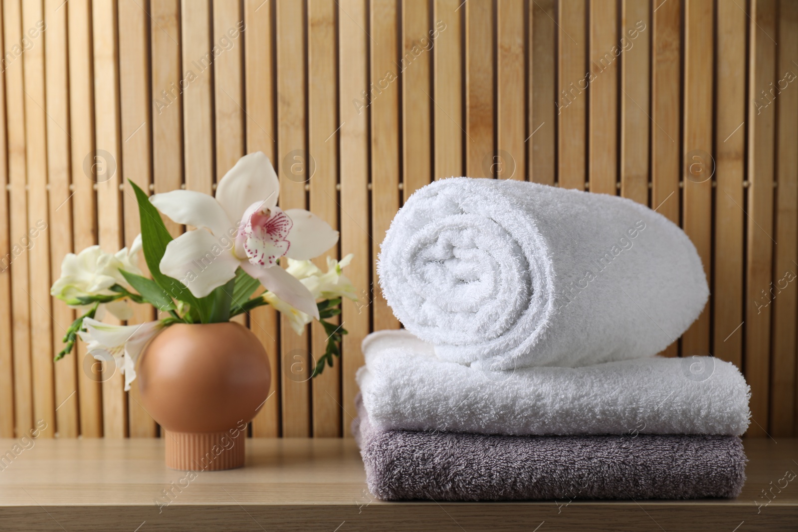 Photo of Terry towels and beautiful flowers on wooden table