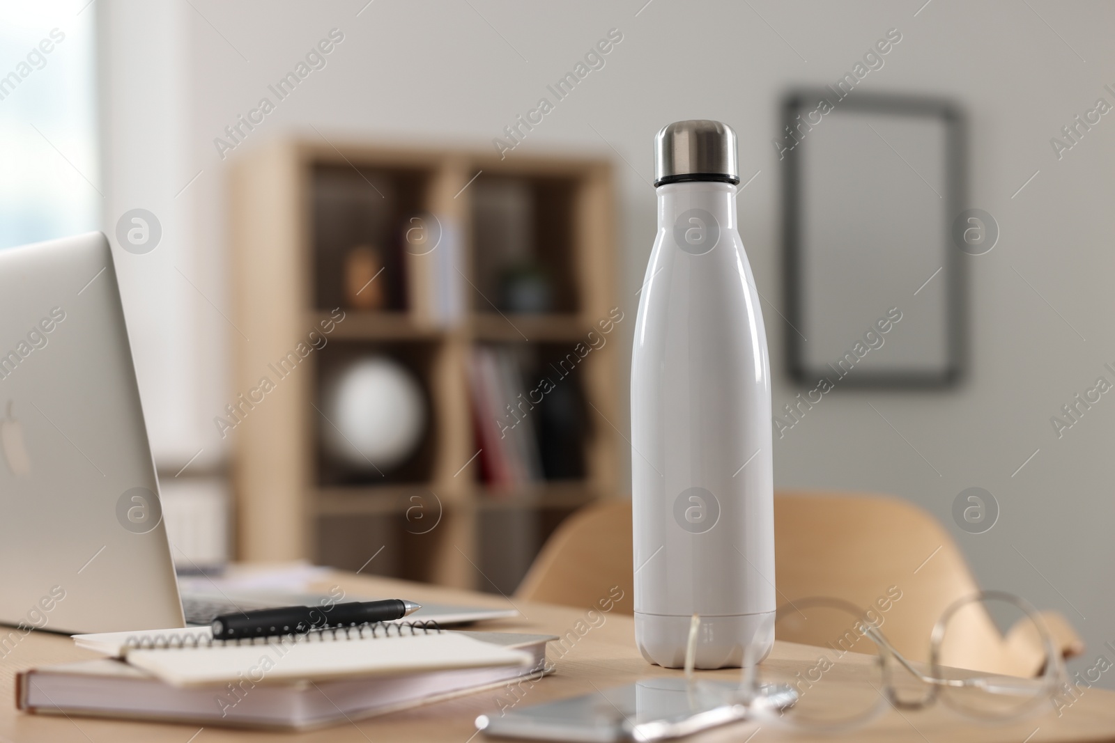 Photo of White thermos bottle on wooden table indoors. Space for text