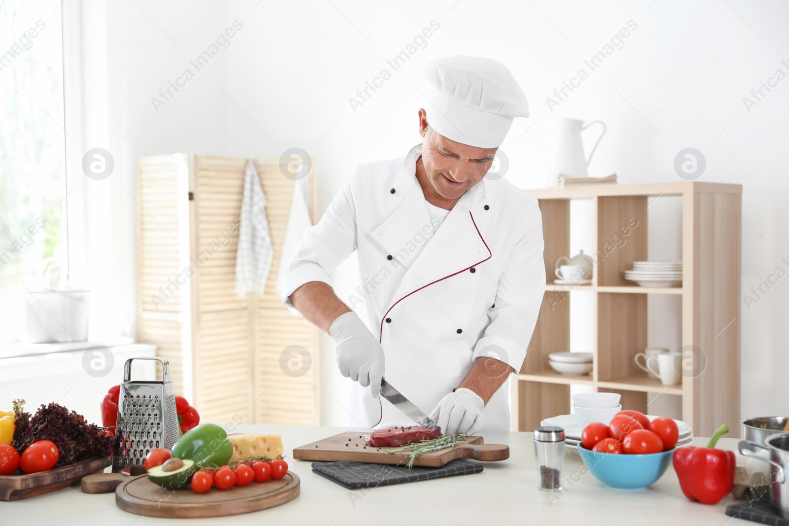 Photo of Professional chef cutting meat on table in kitchen