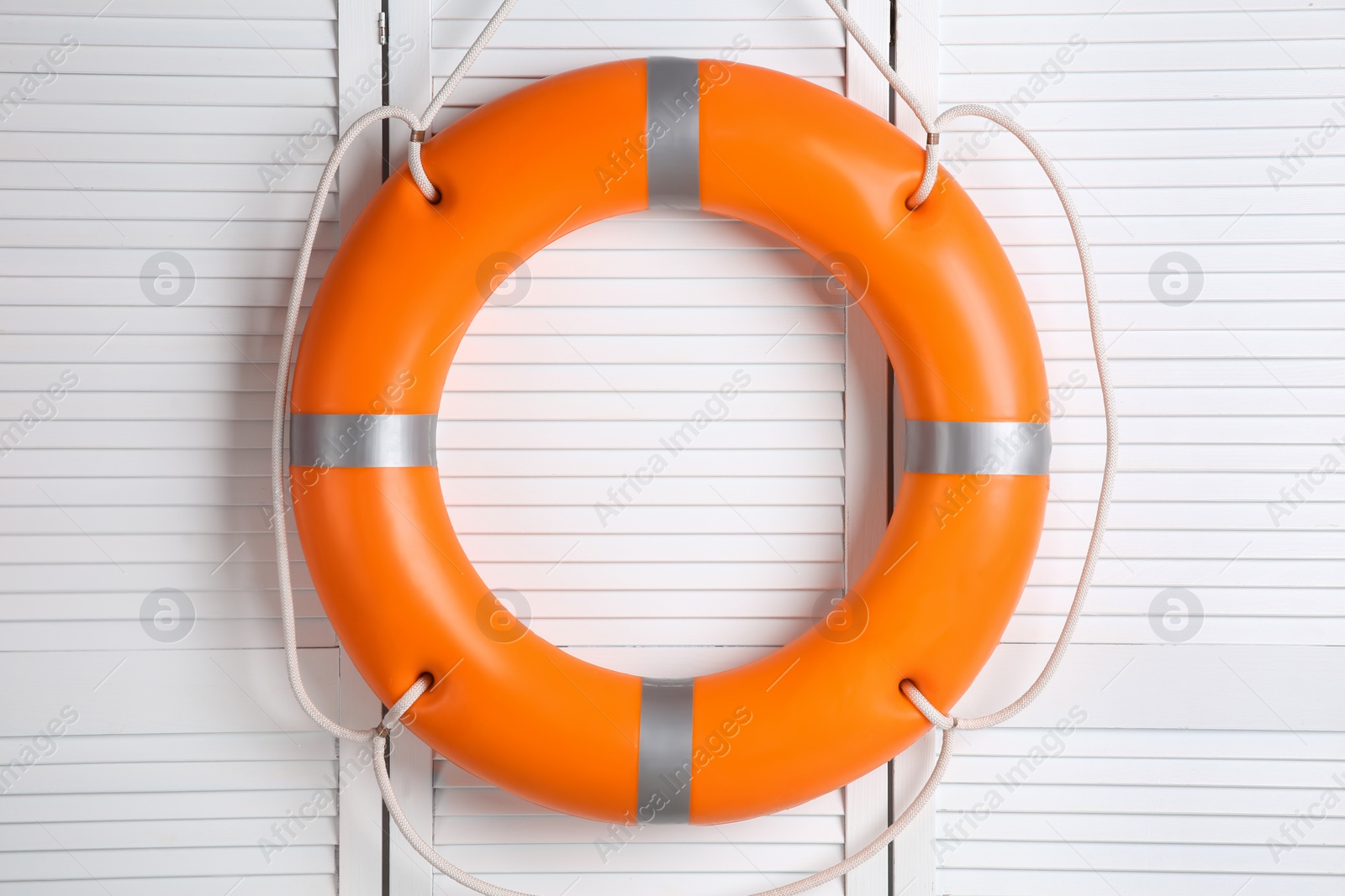 Photo of Orange lifebuoy on white wooden background. Rescue equipment