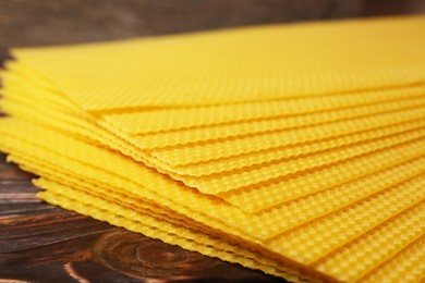 Photo of Natural beeswax sheets on wooden table, closeup