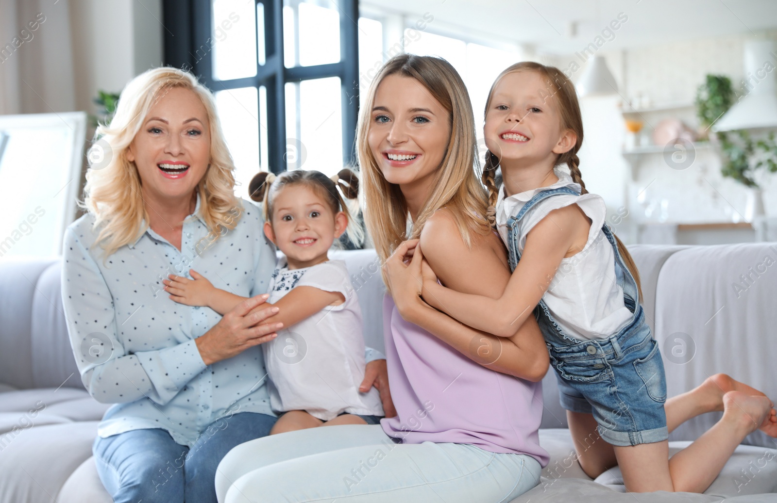 Photo of Young woman with mature mother and little daughters in living room