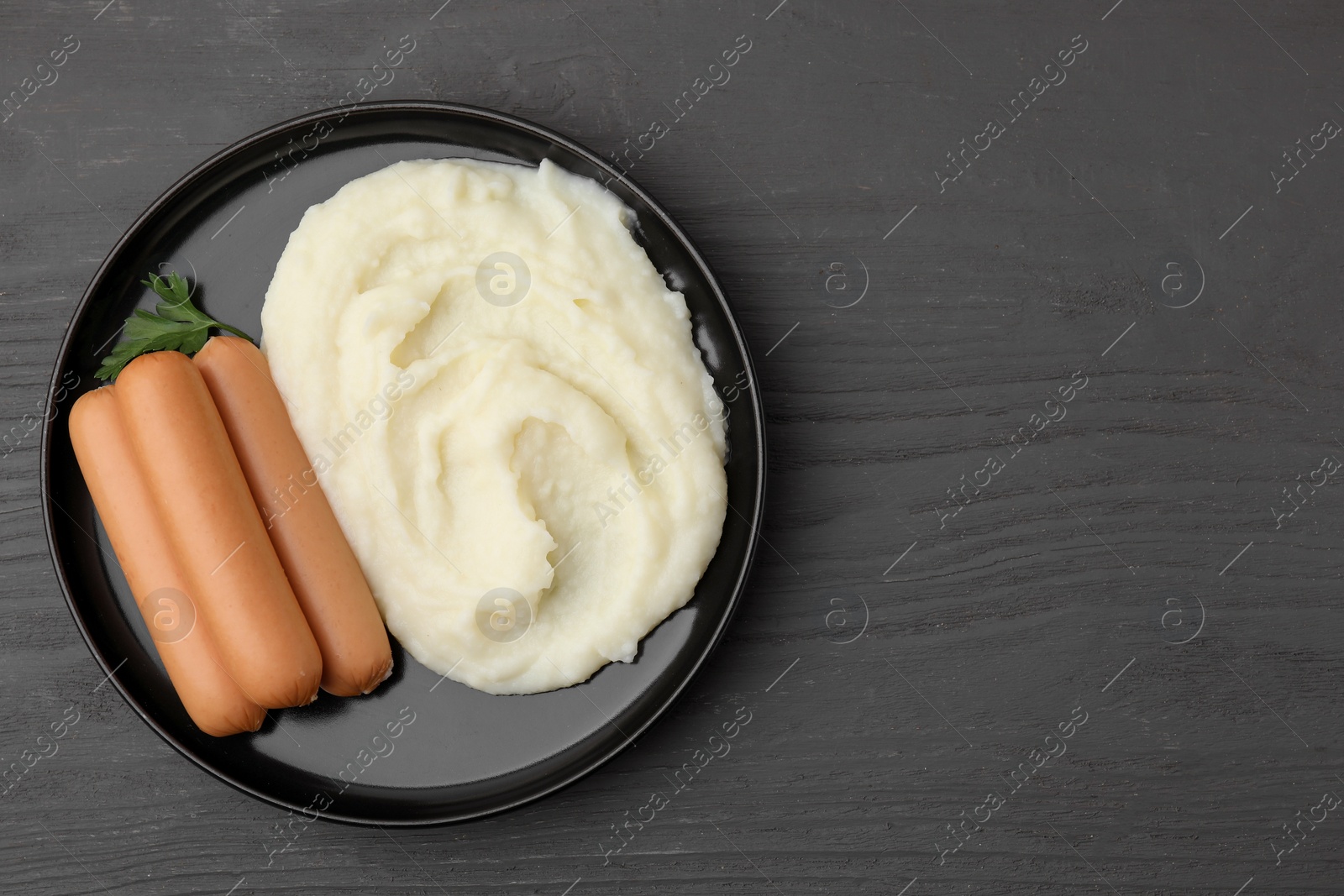 Photo of Delicious boiled sausages, mashed potato and parsley on grey wooden table, top view. Space for text