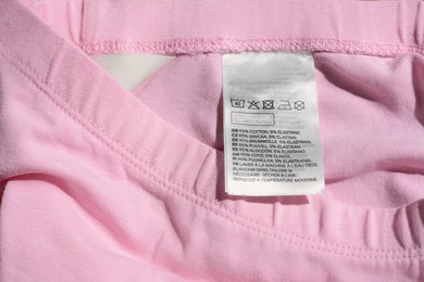 Photo of Clothing label on pink garment, top view