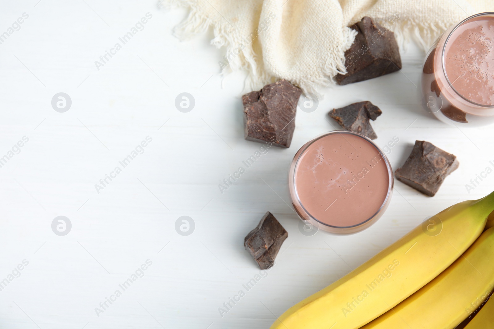 Photo of Yummy chocolate milk and fresh ingredients on white wooden table, flat lay. Space for text