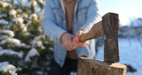 Man chopping wood with axe outdoors on winter day, closeup