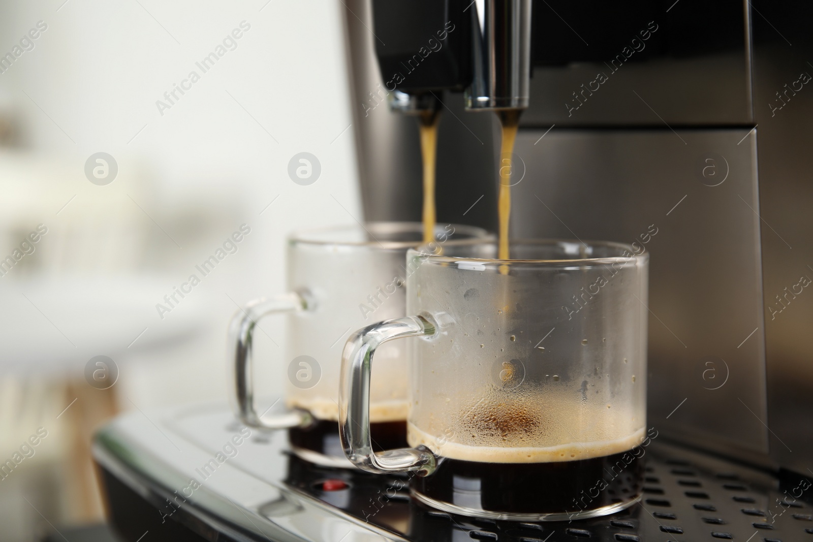 Photo of Espresso machine pouring coffee into glass cups against blurred background, closeup. Space for text