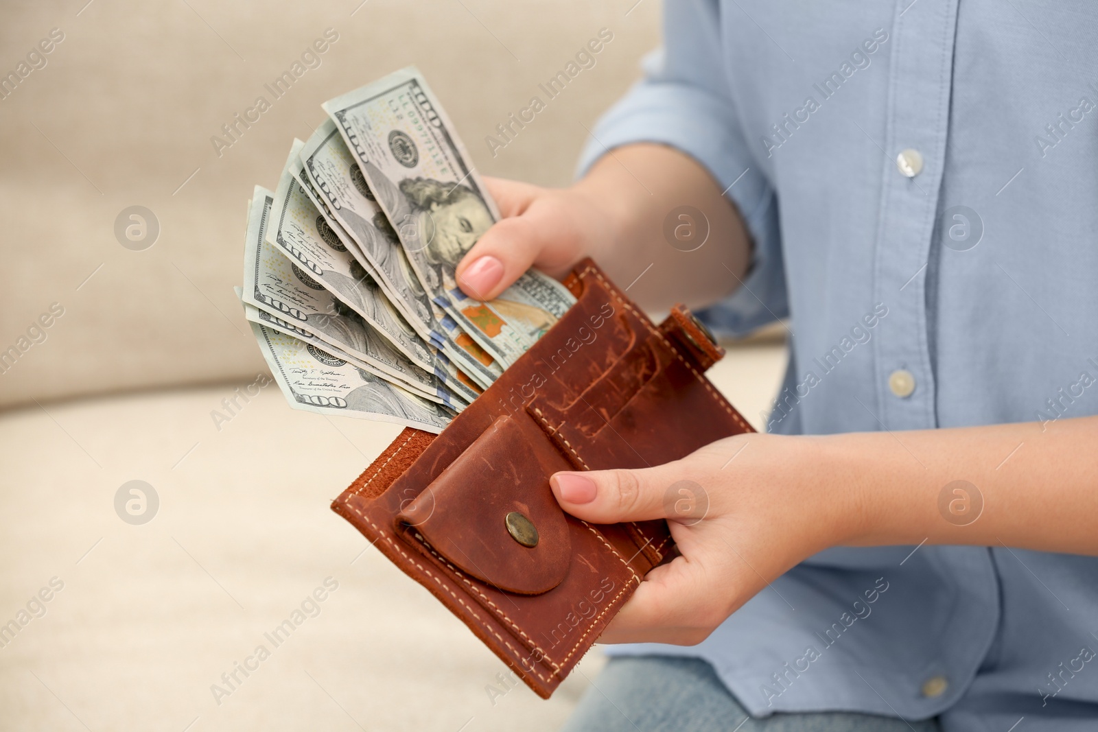 Photo of Woman counting dollar bills indoors, closeup. Money exchange