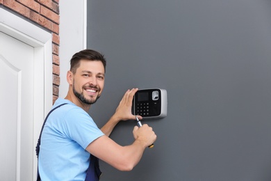 Male technician installing alarm system indoors