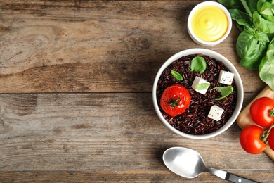 Photo of Flat lay composition with delicious cooked brown rice on wooden table. Space for text