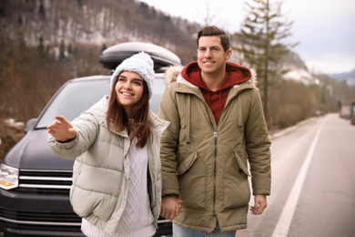 Photo of Happy couple near car on road. Winter vacation