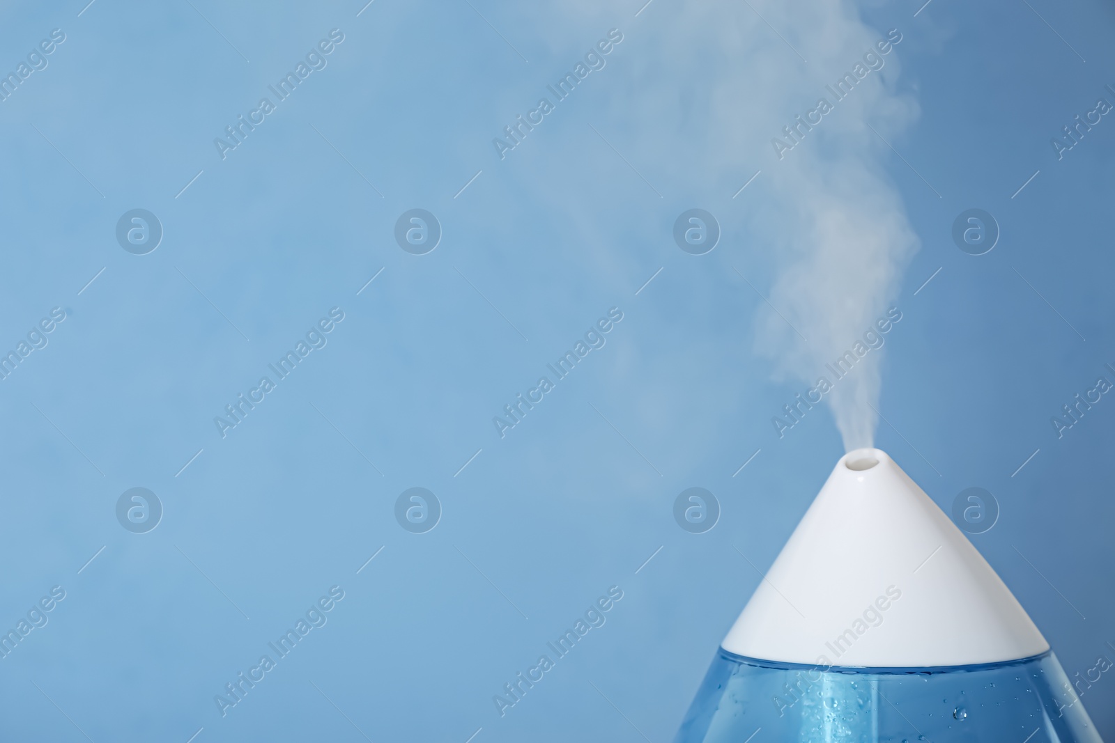 Photo of Modern air humidifier on light blue background, closeup. Space for text