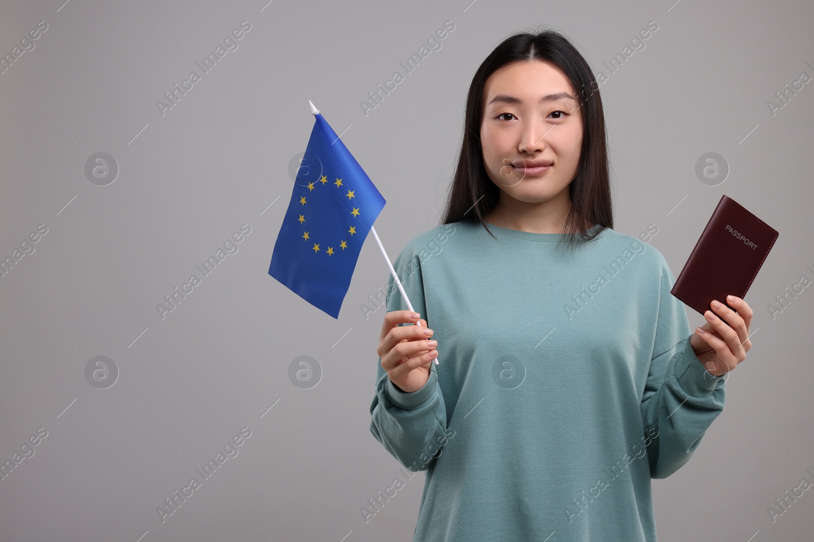 Photo of Immigration to European Union. Woman with passport and flag on grey background, space for text