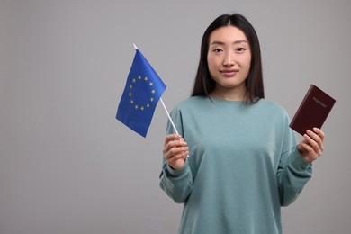 Immigration to European Union. Woman with passport and flag on grey background, space for text