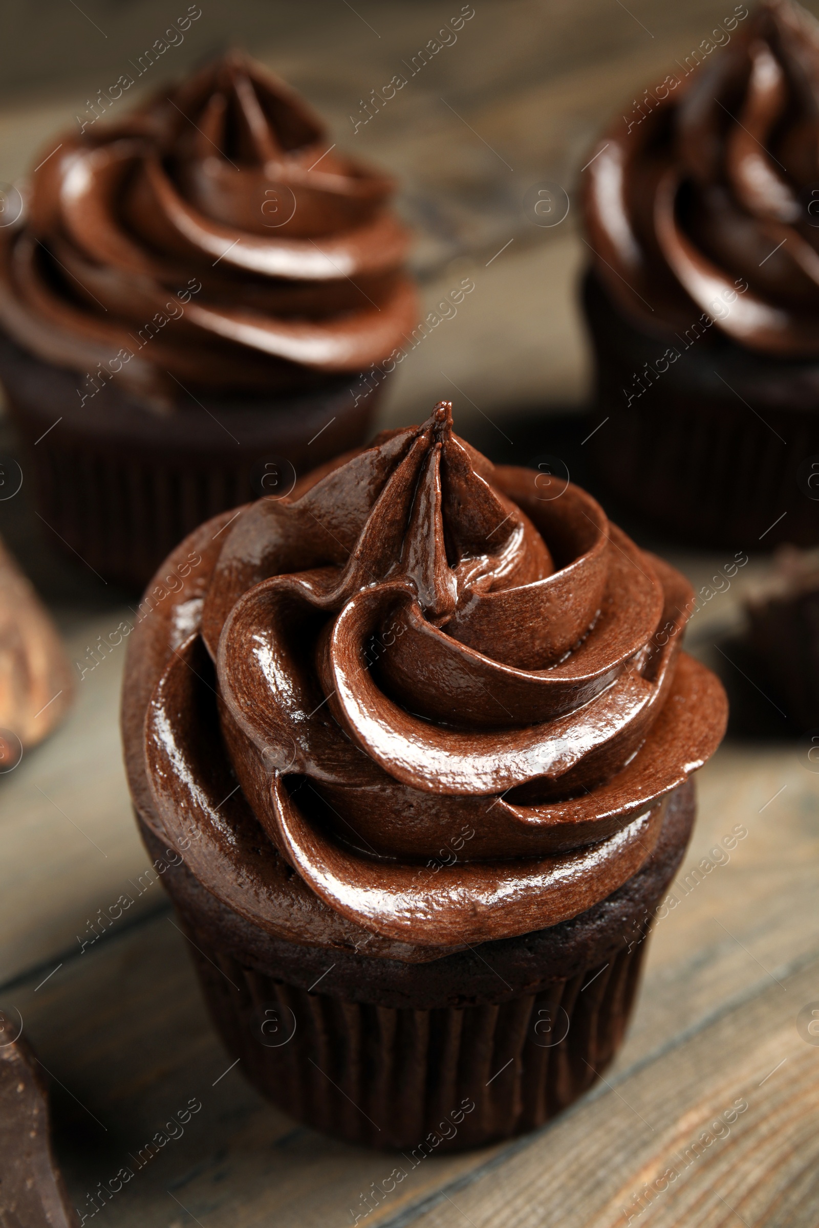 Photo of Delicious chocolate cupcake with cream on wooden table