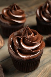 Photo of Delicious chocolate cupcake with cream on wooden table
